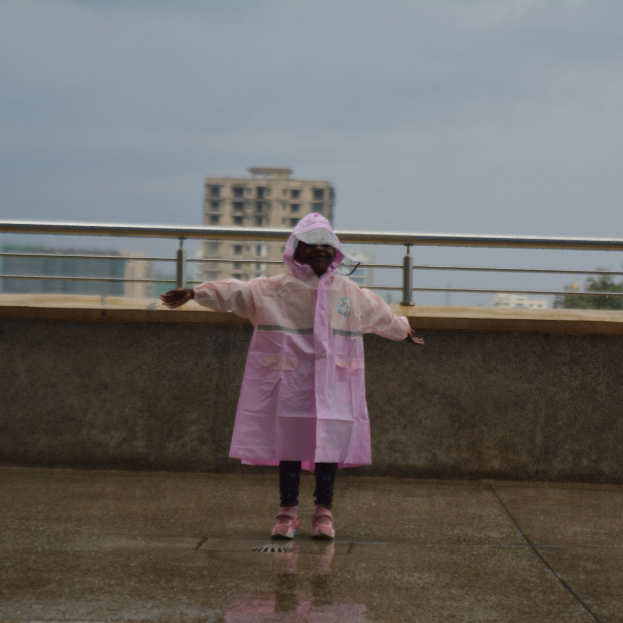 Girl standing on a rooftop with a cityscape in the background