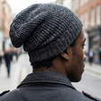 Person wearing a gray knit beanie walking down a city street.