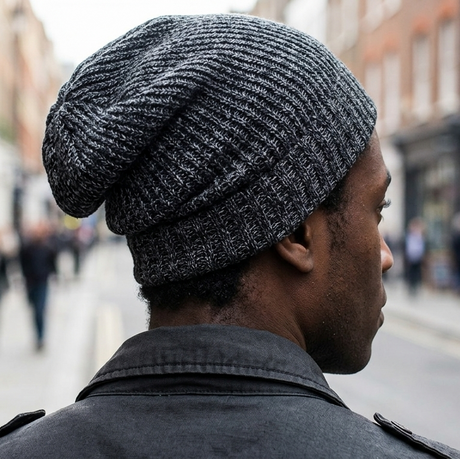 Person wearing a gray knit beanie walking down a city street.