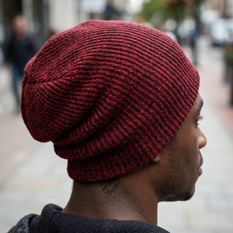 Person wearing a red knit beanie on a blurred street background