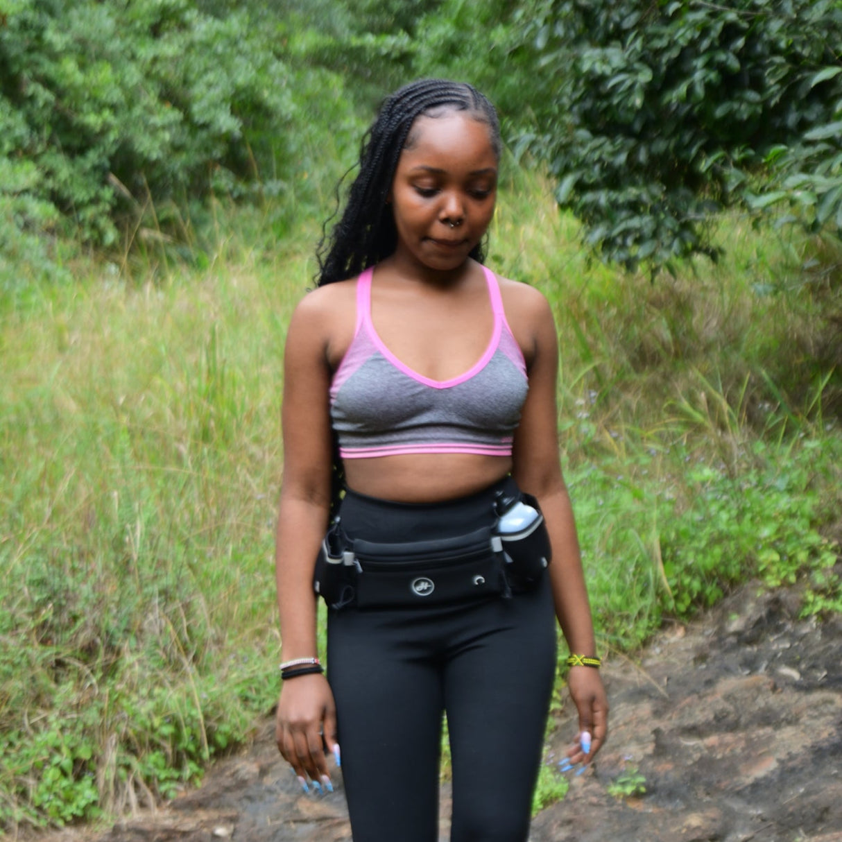 Woman in athletic wear walking on a trail with greenery in the background