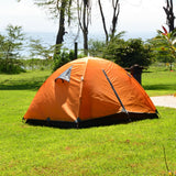 Orange tent on a grassy area with trees and a bench in the background
